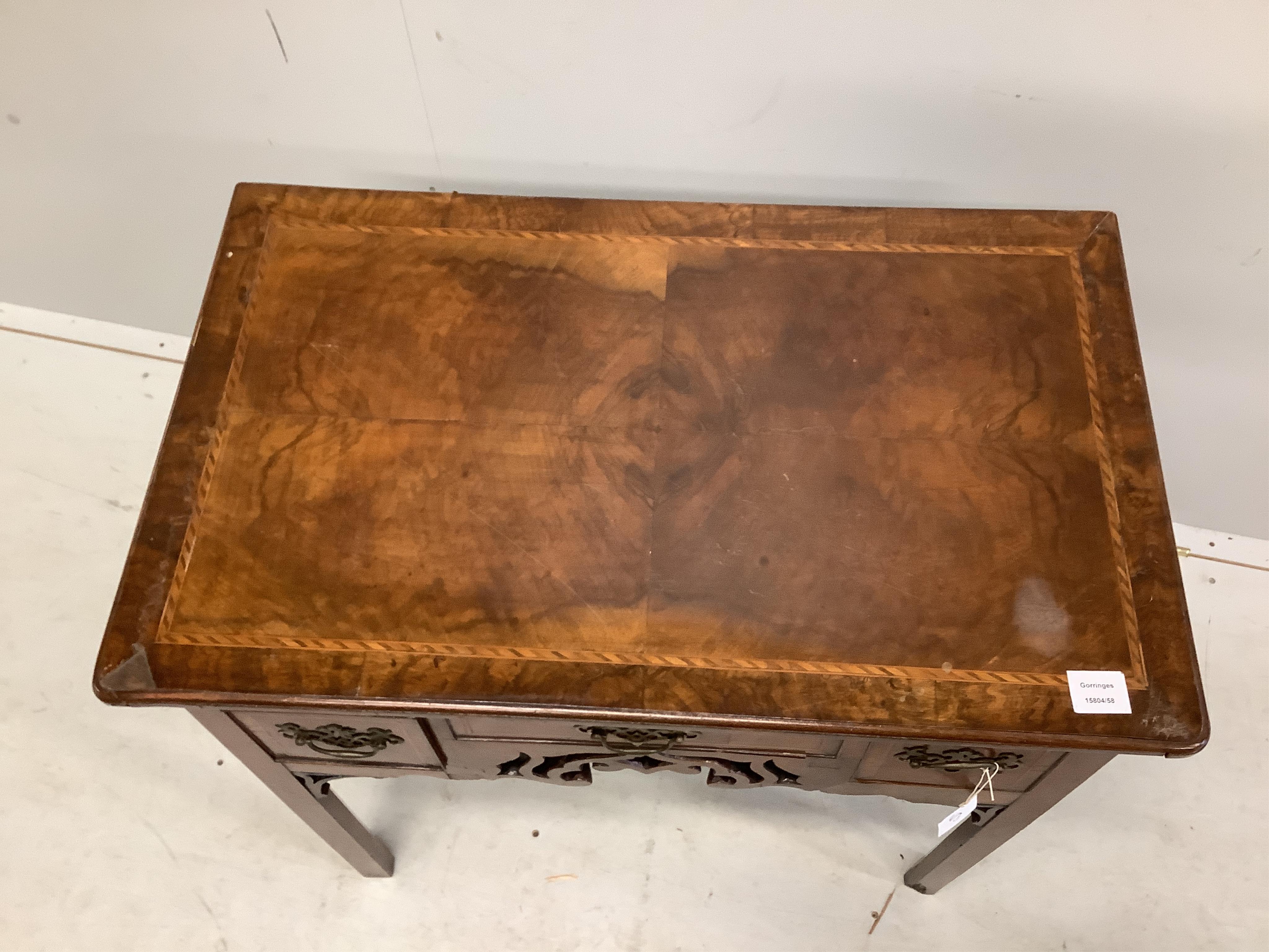 A mid 18th century walnut lowboy quarter veneered with a rectangular top above three drawers and a pierced apron on chamfered legs, width 80cm, depth 49cm, height 73cm. Condition - poor to fair